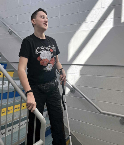 Jeune homme descendant un escalier avec sa canne blanche